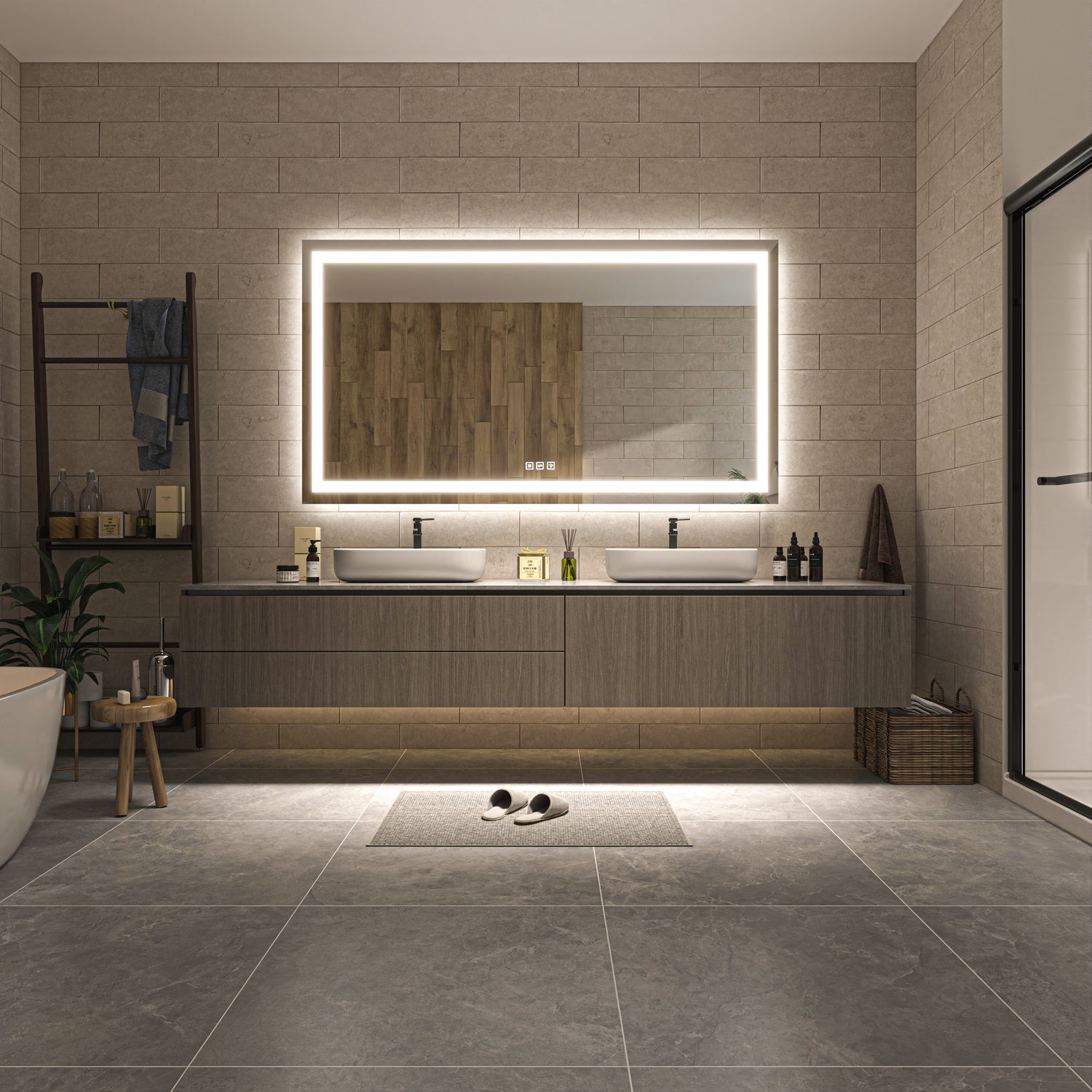 A modern bathroom vanity setup with a large rectangular backlit mirror, double white vessel sinks, a long wood-look floating cabinet, and gray stone tile flooring. A small rug, slippers, shelf, and plant are visible in the room.